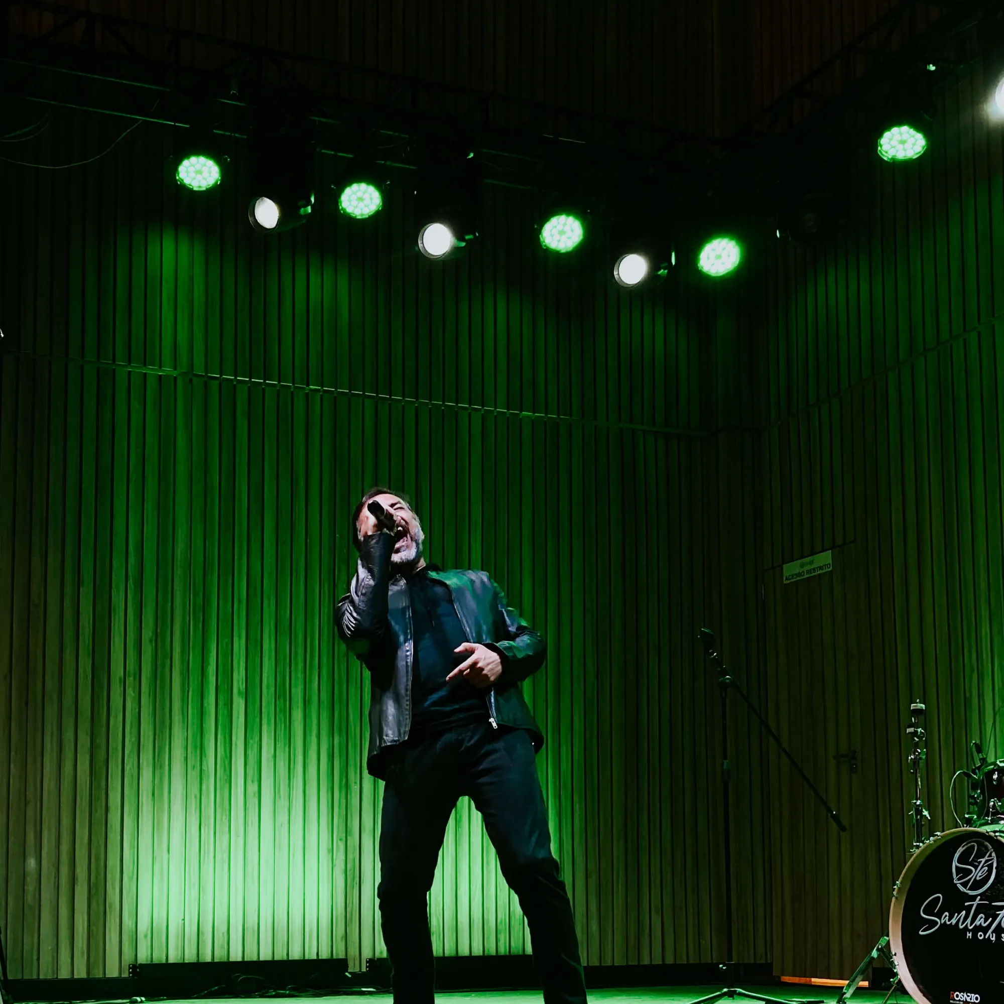 Cantor em palco iluminado de verde durante um show, cobertura de evento em Belém
