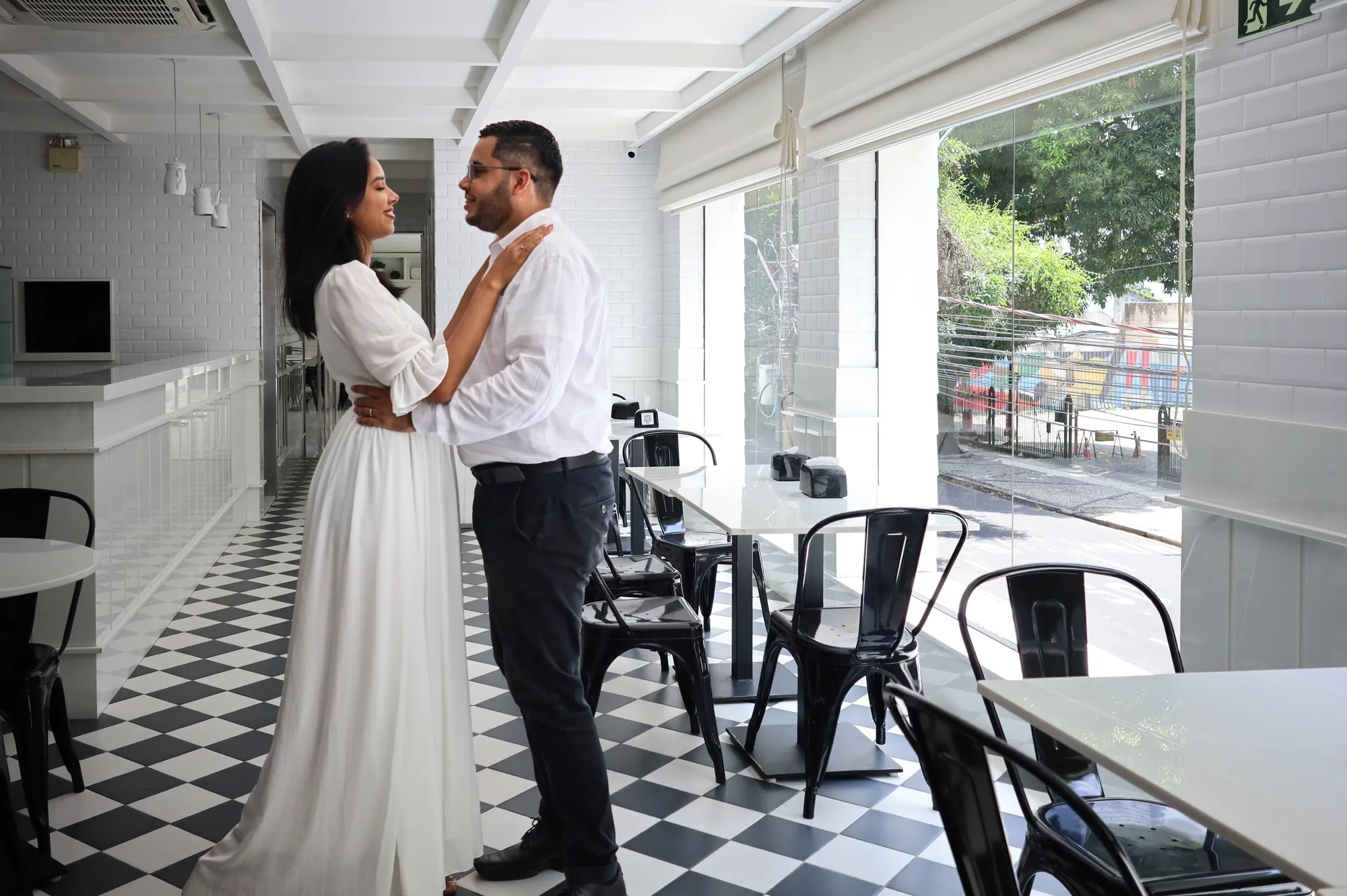 Casal abraçado em corredor envidraçado de piso xadrez