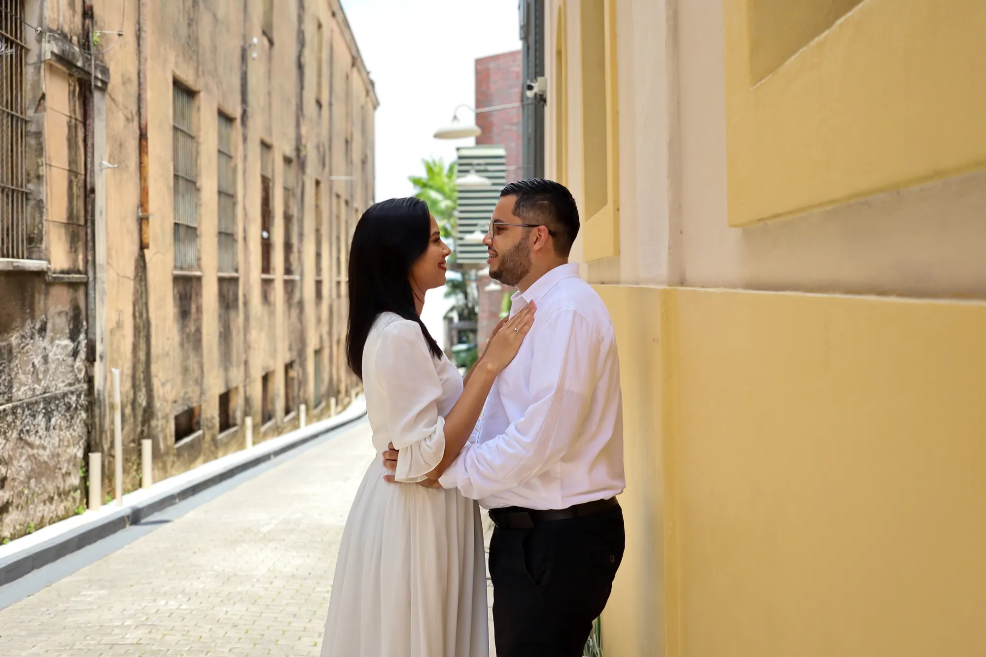 Casal abraçado em rua histórica de Belém, ao lado de fachada amarela