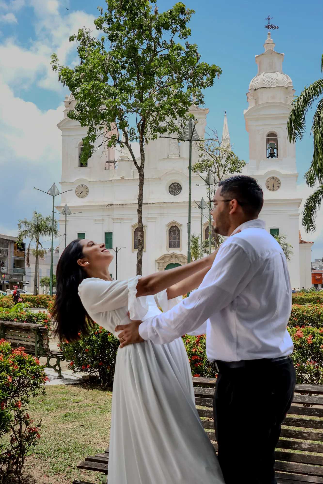 Ensaio pré-wedding em Belém: casal dançando em praça diante de igreja branca